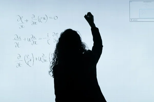 Engineer writing math equations on transparent board.